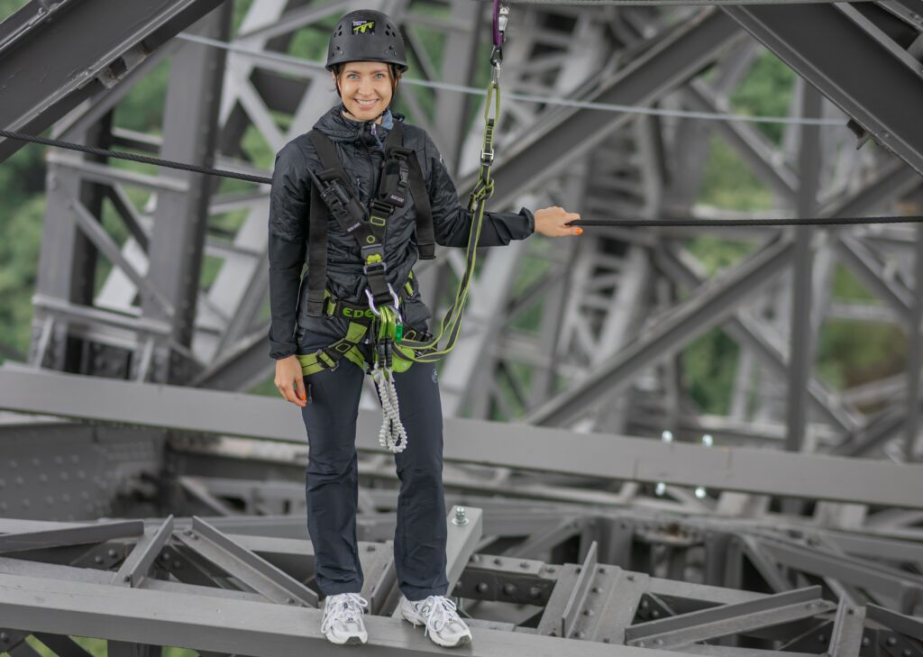 Person steht auf der Müngstener Brücke und überquert diese auf dem Balken